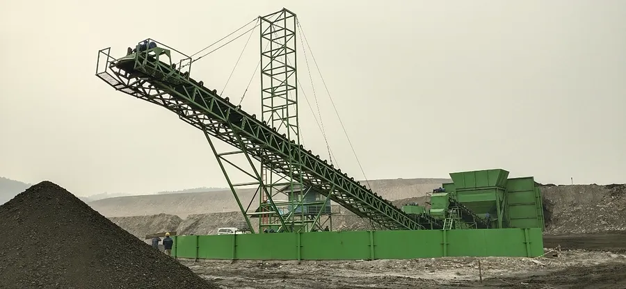 OFN coal crushing plant and inclined stacking conveyor beside a stockpile at a mine site.