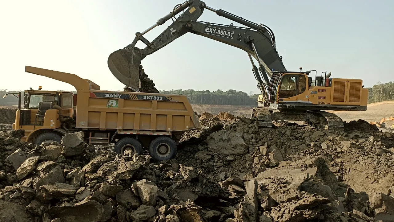 Large excavator loading broken overburden into a rigid haul truck at a working face.