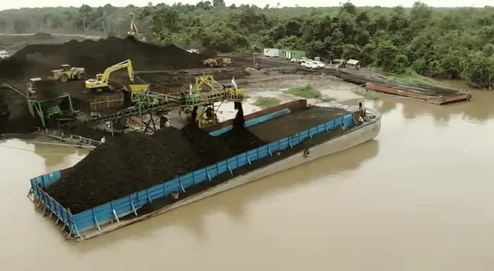 Aerial view of a river loading point with a conveyor filling a barge alongside the bank.